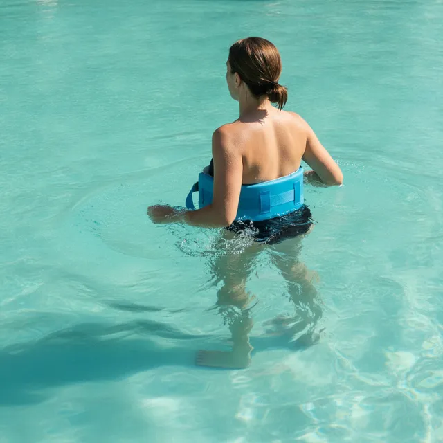 Personne vue de dos courant en eau profonde avec une ceinture de flottaison bleue