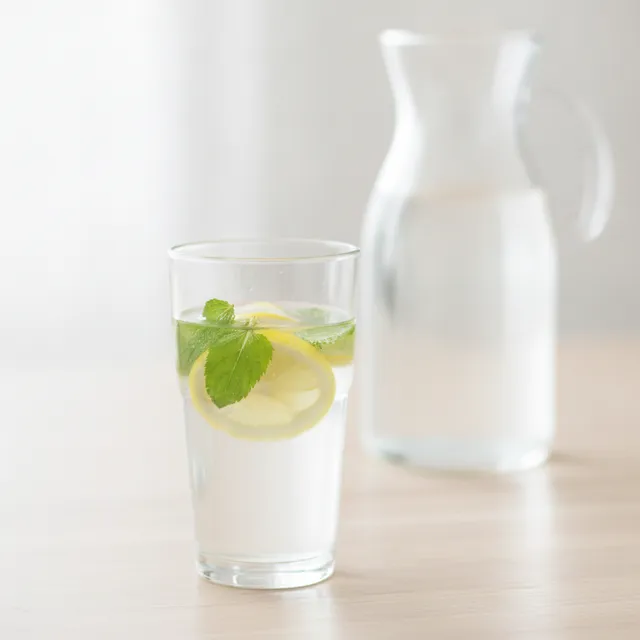 Verre d'eau fraîche avec rondelles de citron et feuilles de menthe sur une table claire
