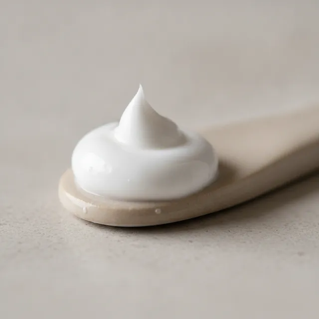 Noisette de crème hydratante blanche onctueuse sur une petite spatule en céramique, gros plan macro