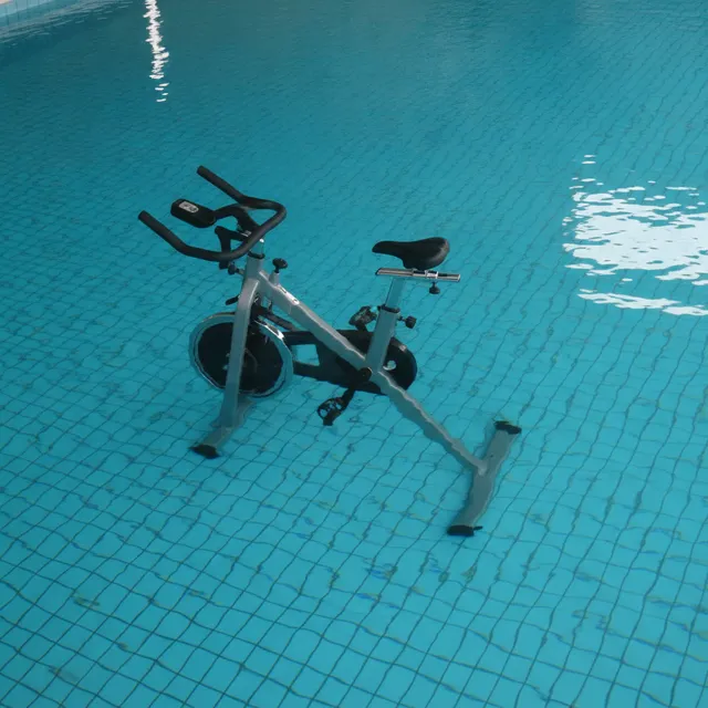 Un vélo d'aquabike immergé dans l'eau turquoise d'une piscine, vu de dessus